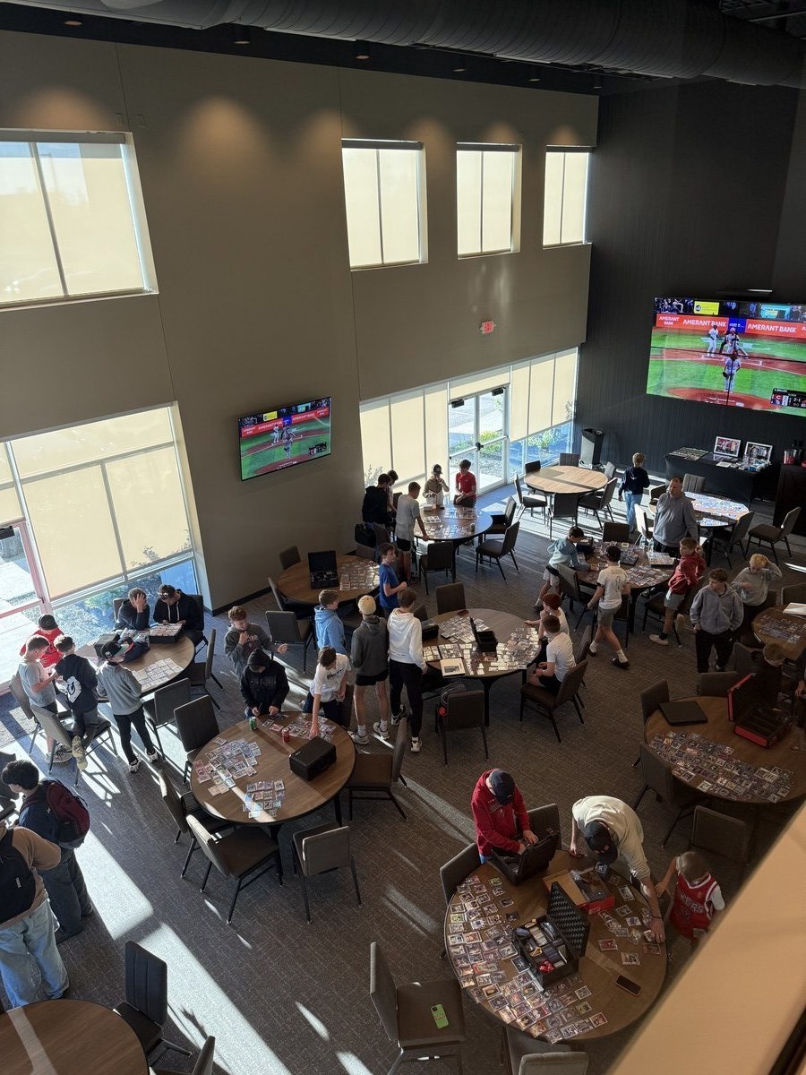 Kids gathered around a table covered in sports cards at Next Gen Card Traders at Revelance