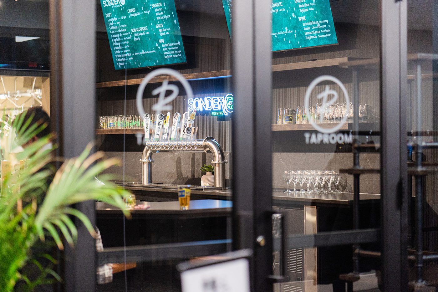 Taphouse entry through glass doors with Sonder neon sign