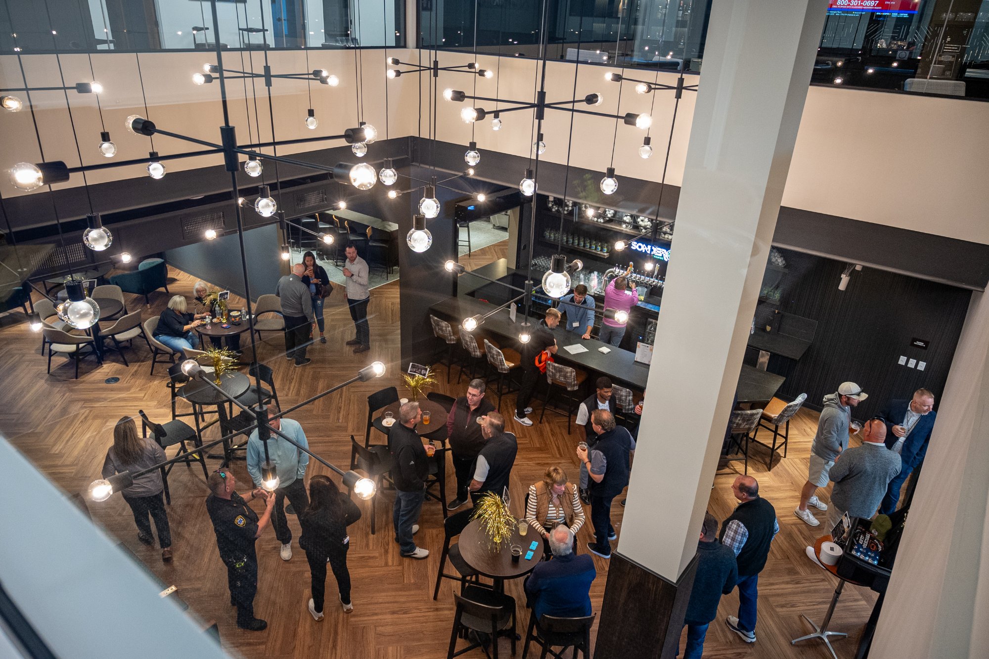 Aerial view of The Taphouse at Revelance during a private event — guests mingling under pendant lights with Sonder bar in background